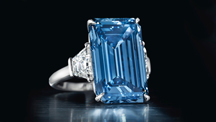 The 14.62 ct. emerald cut Fancy Vivid Blue Oppenheimer diamond is flanked by diamonds in a ring setting. 