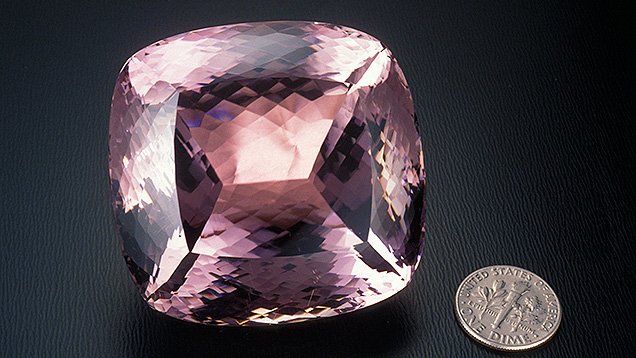 Cut Kunzite with Dime - Quality Factors. This kunzite from Minas Gerais, Brazil, weighs 648.10 carats. It’s shown next to a dime to demonstrate scale. - Robert Weldon, courtesy M. Meienhalder