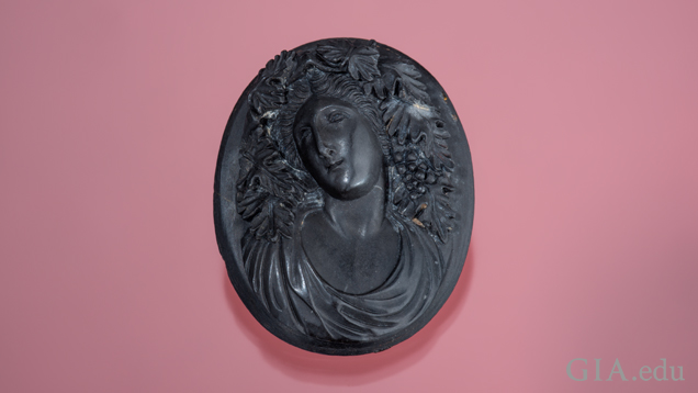 The goddess Bacchante is carved in high relief in black lava and shows fine detail of leaves and clusters of grapes in her hair. The goddess Bacchante is carved in high relief in black lava and shows fine detail of leaves and clusters of grapes in her hair.