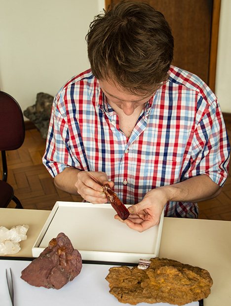 examining 615ct. topaz. Alexander Kreis contemplates the original 615 ct Imperial topaz crystal. Photo courtesy Sonja Kreis Unique Jewelry.