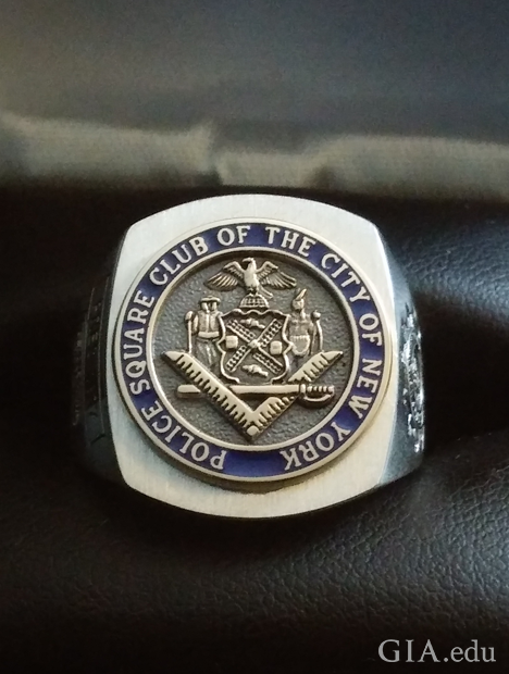 一枚中心为圆圈且带有浮雕标志的方形戒指。上面刻有“Police Square Club of the City of New York”(纽约市警察局共济会)。 一枚中心为圆圈且带有浮雕标志的方形戒指。上面刻有“Police Square Club of the City of New York”(纽约市警察局共济会)。