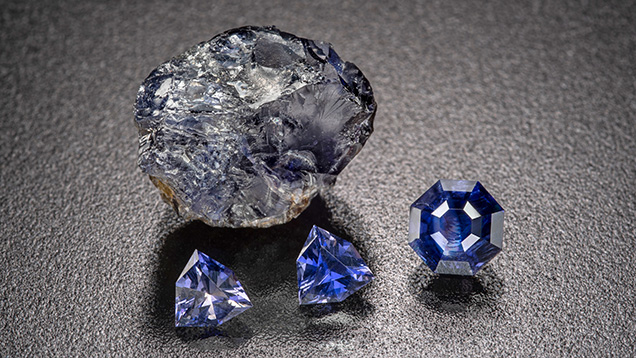 Figure 11. Rough and cut iolite from the Blue Arrow occurrence. The faceted stones weigh up to 1.15 ct, with the two matching triangular stones weighing approximately 0.8 ct in total. Photo by Michael Bainbridge. Figure 11. Rough and cut iolite from the Blue Arrow occurrence. The faceted stones weigh up to 1.15 ct, with the two matching triangular stones weighing approximately 0.8 ct in total. Photo by Michael Bainbridge.