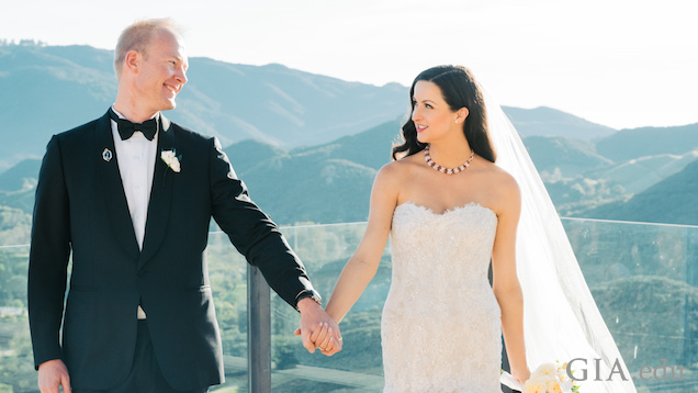 黒いタキシードを着た新郎と白いウェディングドレスを着た新婦が、結婚式で手を握り、見つめ合う。背景にはカリフォルニアの山々が見える。 黒いタキシードを着た新郎と白いウェディングドレスを着た新婦が、結婚式で手を握り、見つめ合う。背景にはカリフォルニアの山々が見える。