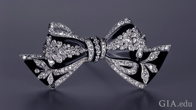 Bow brooch with stripe-like sections of black onyx between diamond sections. Bow brooch with stripe-like sections of black onyx between diamond sections.