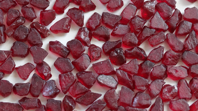 A close-up image of a pile of rough rubies