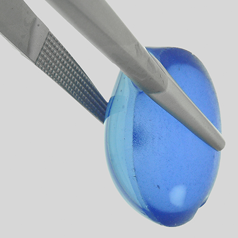 SU15-GNI-fig15_185351-468x468.jpg. Synthetic star cabochon showing shallow coloration with a colorless circular area of repolishing.