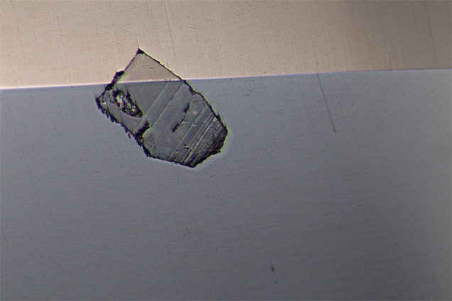 Surface-breaking crystal seen in red spinel.