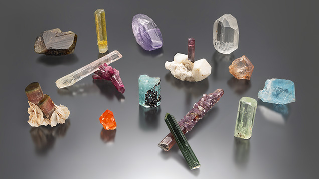 Figure 1. A selection of pegmatite gem crystals, including beryl, chrysoberyl, garnet, spodumene, topaz, and tourmaline. Photo by Mimi Travis; courtesy of the GIA Museum collection. Figure 1. A selection of pegmatite gem crystals, including beryl, chrysoberyl, garnet, spodumene, topaz, and tourmaline. Photo by Mimi Travis; courtesy of the GIA Museum collection.