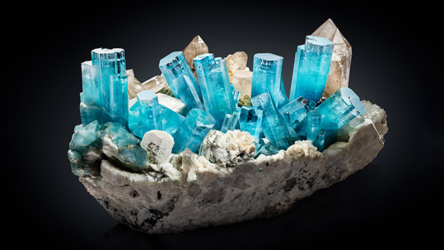 Figure 14. The “King of Kashmir” aquamarine crystal group, measuring 45 cm tall and 80 cm wide, was collected in 2019 from a miarolitic pegmatite dike in the remote Nyet Bruk region of the Skardu District in northern Pakistan (Trinchillo, 2020). It is considered by many to be one of the most significant gem mineral specimens found in the modern era. Photo by James Elliott/Fine Minerals International; courtesy of Daniel Trinchillo. Figure 14. The “King of Kashmir” aquamarine crystal group, measuring 45 cm tall and 80 cm wide, was collected in 2019 from a miarolitic pegmatite dike in the remote Nyet Bruk region of the Skardu District in northern Pakistan (Trinchillo, 2020). It is considered by many to be one of the most significant gem mineral specimens found in the modern era. Photo by James Elliott/Fine Minerals International; courtesy of Daniel Trinchillo.
