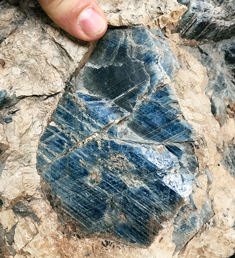 Figure 4. A large sapphire crystal in a syenitic pegmatite host rock from Pegmatite 298 in the Ilmen Mountains mineralogical reserve, Ural Mountains, Russia. Photo by Peter Lyckberg; courtesy of the Ilmen Mineralogical Museum. Figure 4. A large sapphire crystal in a syenitic pegmatite host rock from Pegmatite 298 in the Ilmen Mountains mineralogical reserve, Ural Mountains, Russia. Photo by Peter Lyckberg; courtesy of the Ilmen Mineralogical Museum.