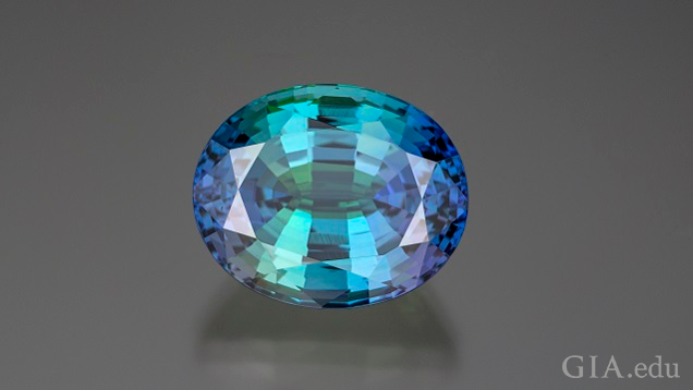 An oval shaped bicolor tanzanite has purple on each side with blue-green in the middle. An oval shaped bicolor tanzanite has purple on each side with blue-green in the middle.