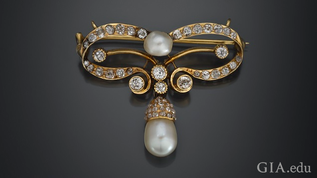 A bow forms the main brooch and a pearl pendent hangs from the bow’s center bottom. A bow forms the main brooch and a pearl pendent hangs from the bow’s center bottom.