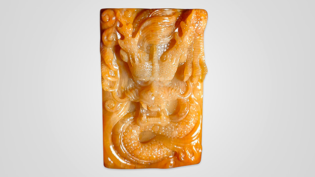 Figure 1. Chalcedony petrified tree fern is carved as an ornamental gem material. This 60 × 40 mm dragon carving has a uniform texture and bright color. Photo by Hai-Long Wang. Figure 1. Chalcedony petrified tree fern is carved as an ornamental gem material. This 60 × 40 mm dragon carving has a uniform texture and bright color. Photo by Hai-Long Wang.