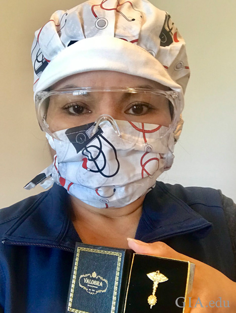 一名带着护目镜和口罩的护士,手持一个装有抗击新冠病毒别针的盒子。 一名带着护目镜和口罩的护士,手持一个装有抗击新冠病毒别针的盒子。