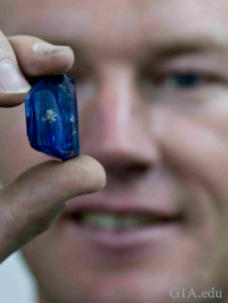 Man holds a large piece of rough tanzanite.